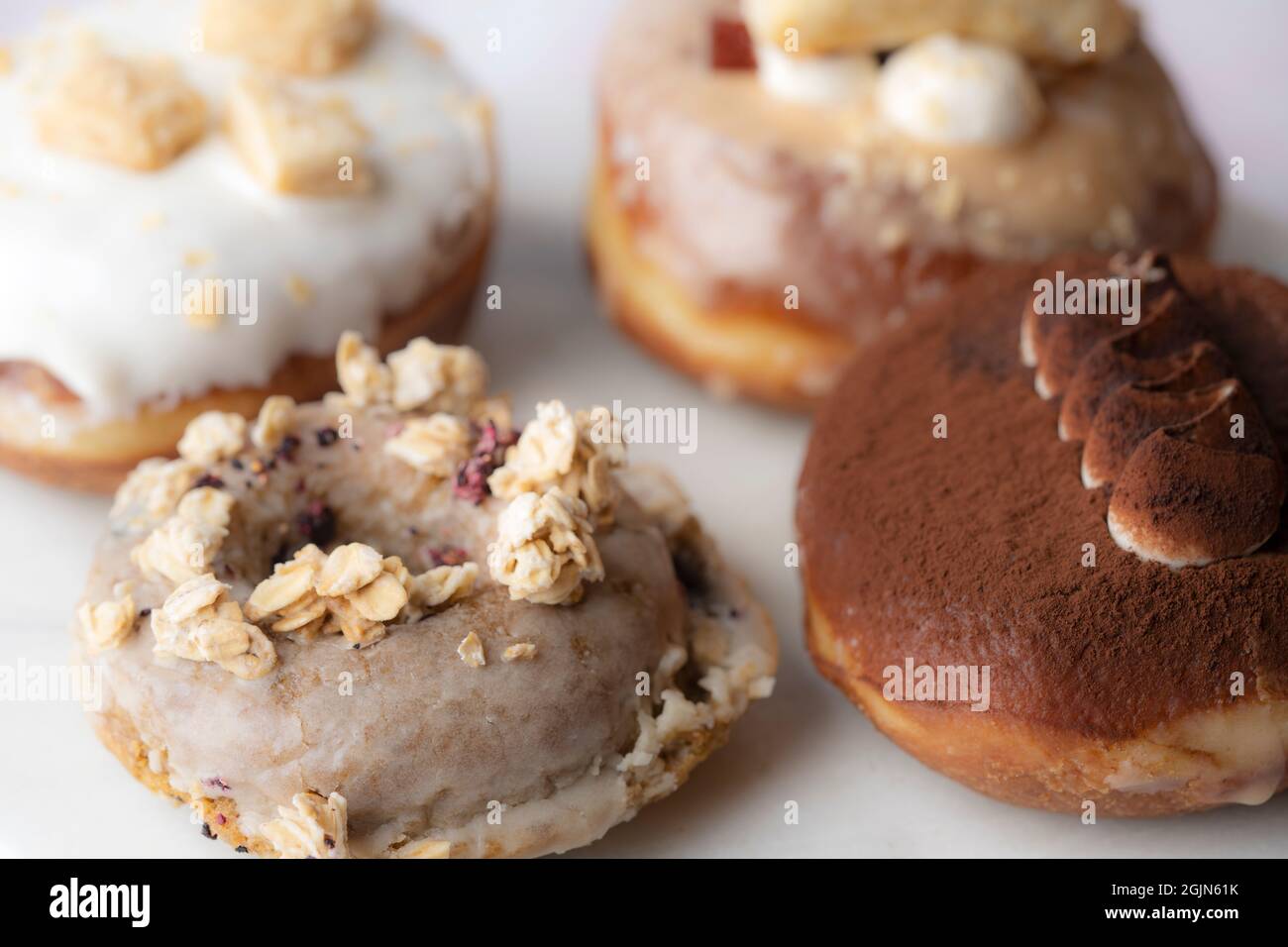 Primer plano de varios tipos de donuts en un plato de mármol, comida Foto de stock