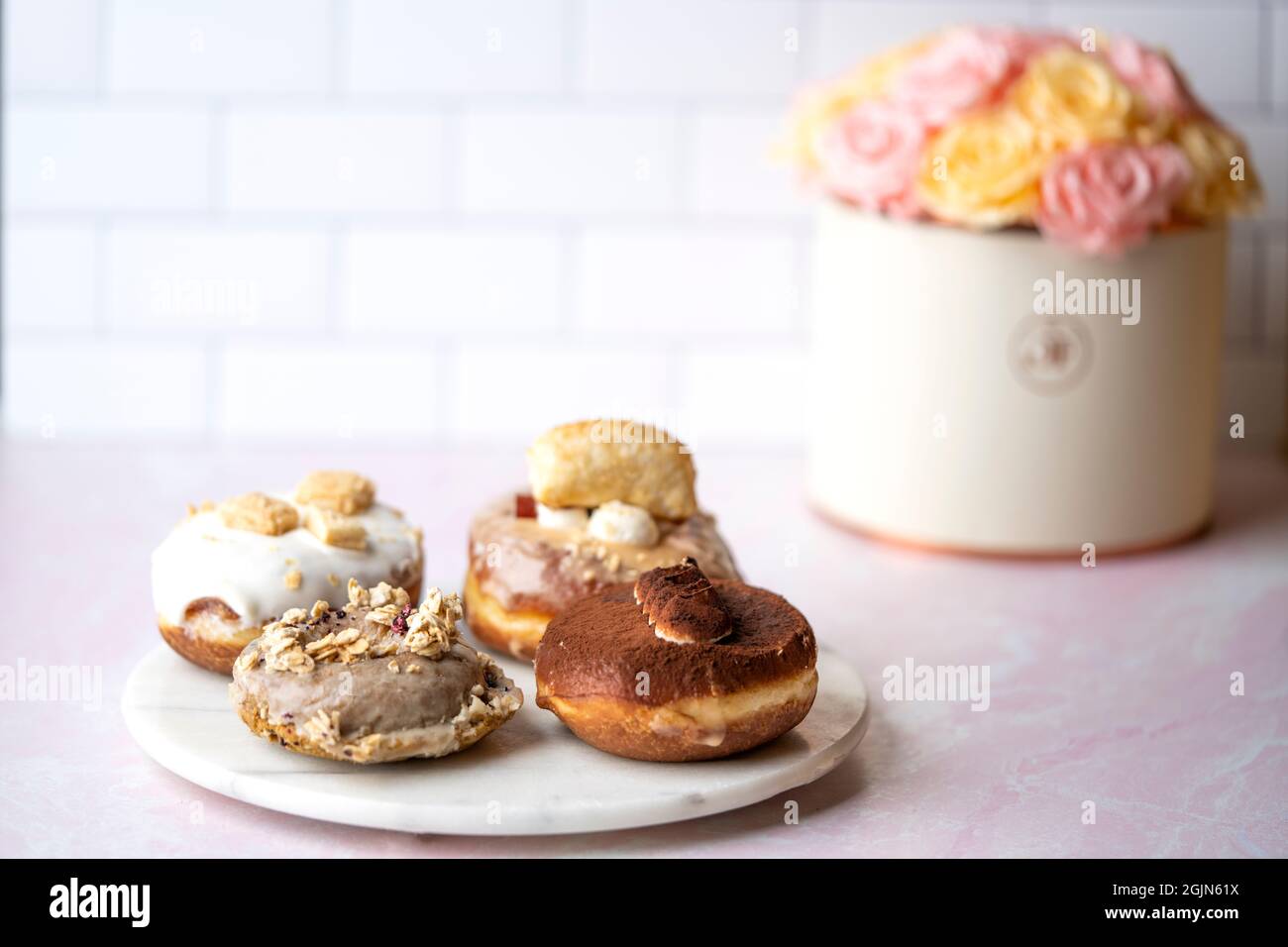 Varios tipos de donuts en un plato de mármol, flores en el fondo Comida Foto de stock