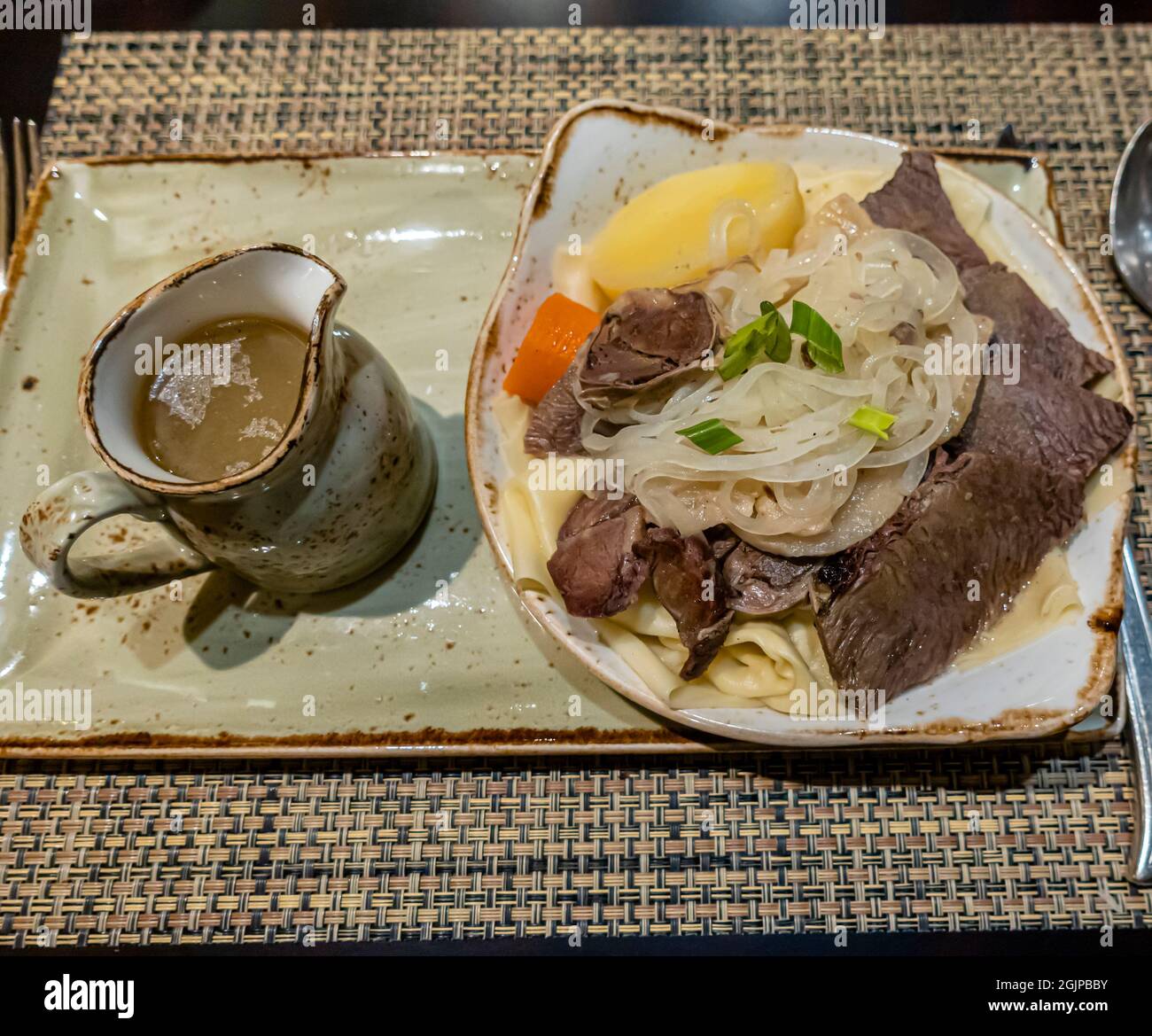 Mutton Beshbarmak, tradicional Kazajstán y Kirguistán, y plato general de Asia Central, servido en un plato con cebollas, patatas, zanahoria y bulones Foto de stock