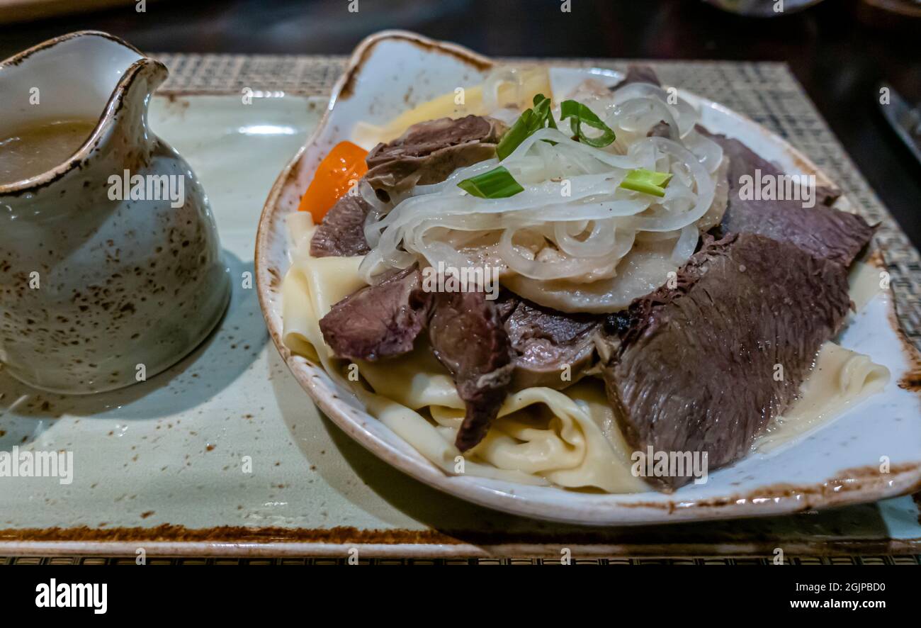 Mutton Beshbarmak, tradicional Kazajstán y Kirguistán, y plato general de Asia Central, servido en un plato con cebollas, patatas, zanahoria y bulones Foto de stock