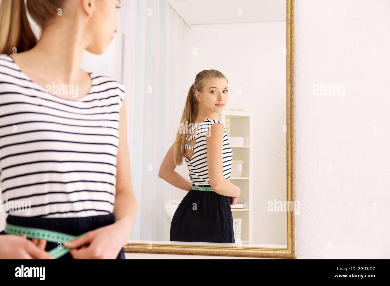 Concepto de dieta. Mujer joven con cinta métrica mirando en el espejo  Fotografía de stock - Alamy