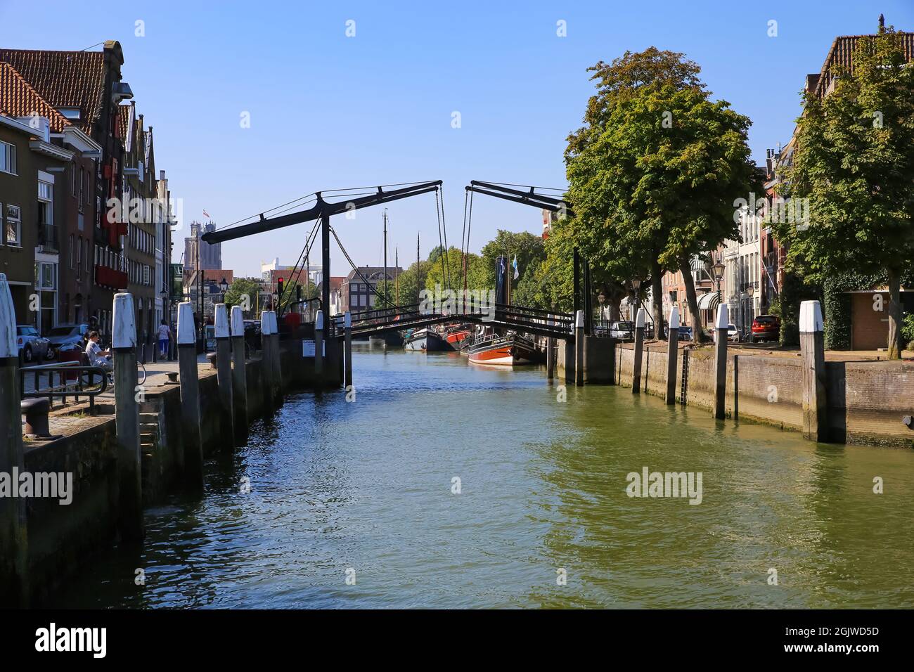 Dordrecht, Países Bajos - Julio de 9. 2021: Vista sobre el canal de agua en el típico puente levadizo holandés, barcos y casas antiguas contra el cielo azul de verano Foto de stock