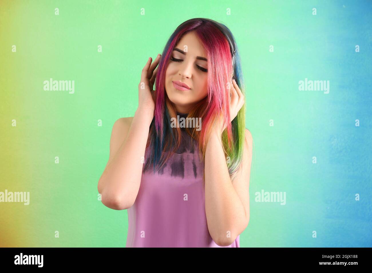 Concepto de peinado de moda. Mujer joven con coloridos cabellos teñidos  para escuchar música de fondo en color Fotografía de stock - Alamy