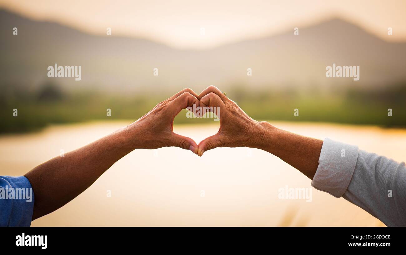 Concepto de amor y día de San Valentín. Una feliz pareja mayor mostrando signo de corazón, símbolo de amor, matrimonio feliz, salud de la tercera edad y relación Fotografía de stock - Concepto de amor y día de San Valentín. Una feliz pareja mayor mostrando signo de corazón, símbolo de amor, matrimonio feliz, salud de la tercera edad y relación Fotografía de stock -