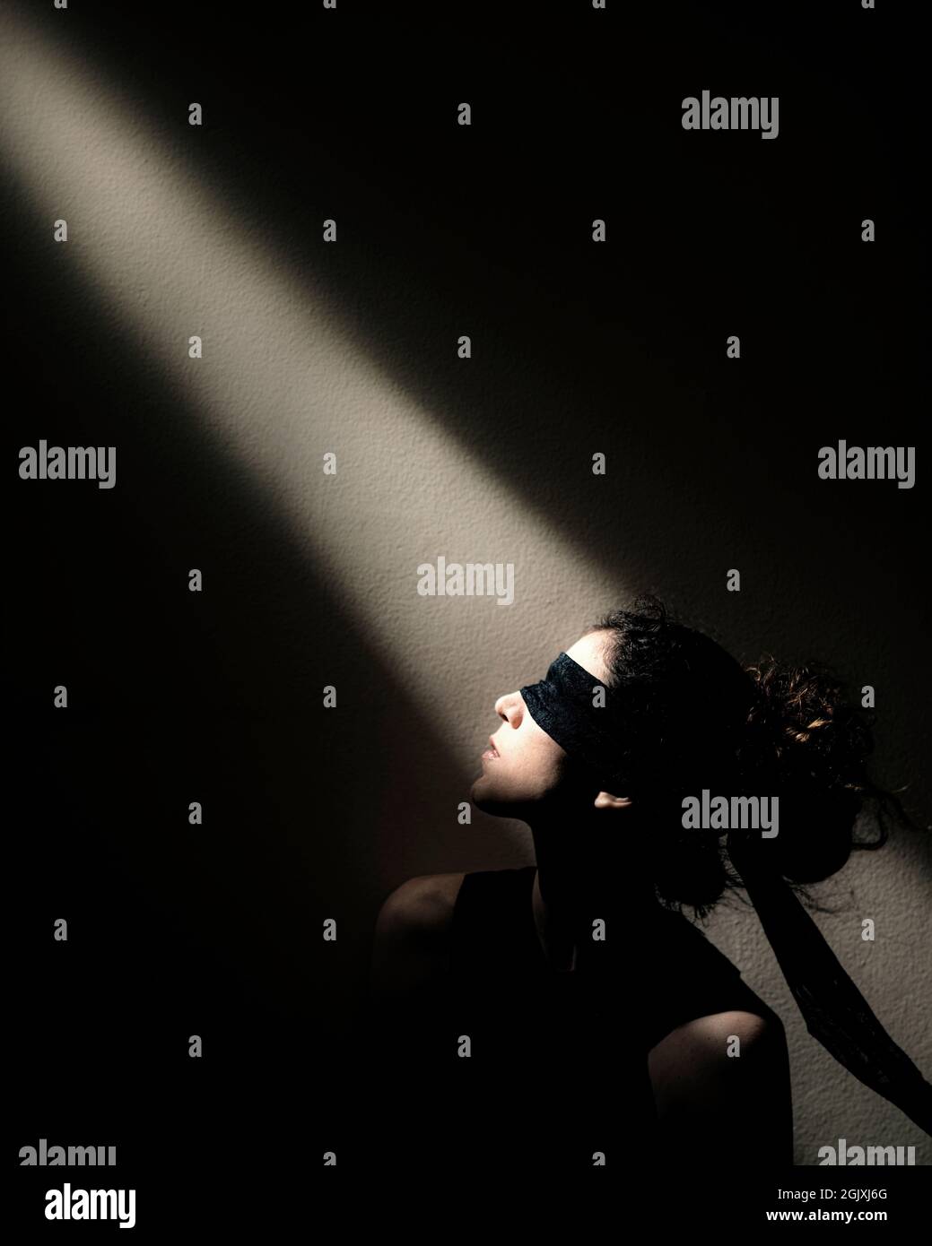 Mujer con los ojos vendados 'mira' a un rayo de luz - Buscando su visión Foto de stock