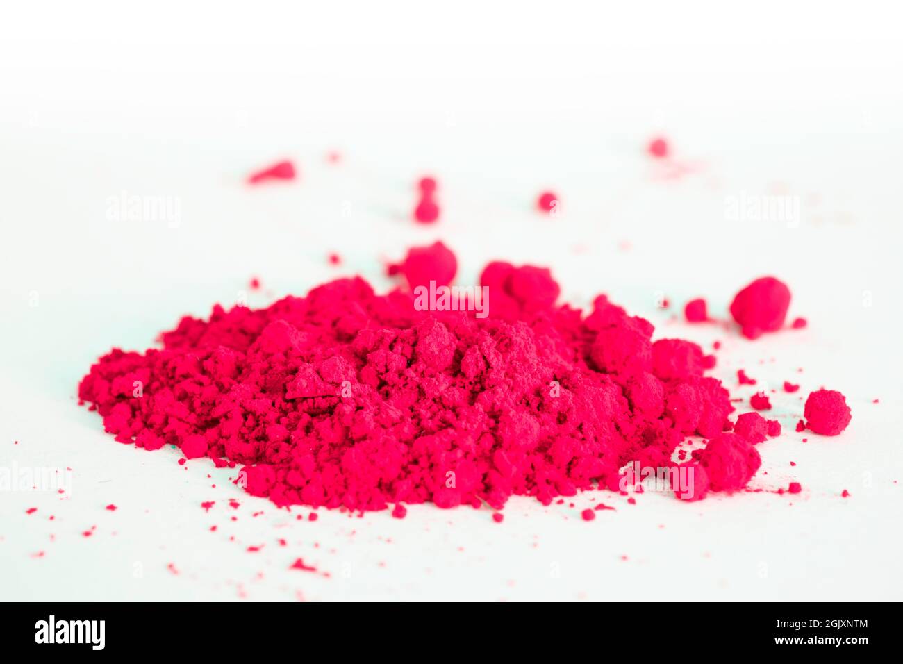 Primer plano de una porción de pigmento rojo aislado sobre blanco. El  pigmento se puede utilizar como base para maquillaje o mezclado con aceite  de linaza para hacer pintura al aceite Fotografía