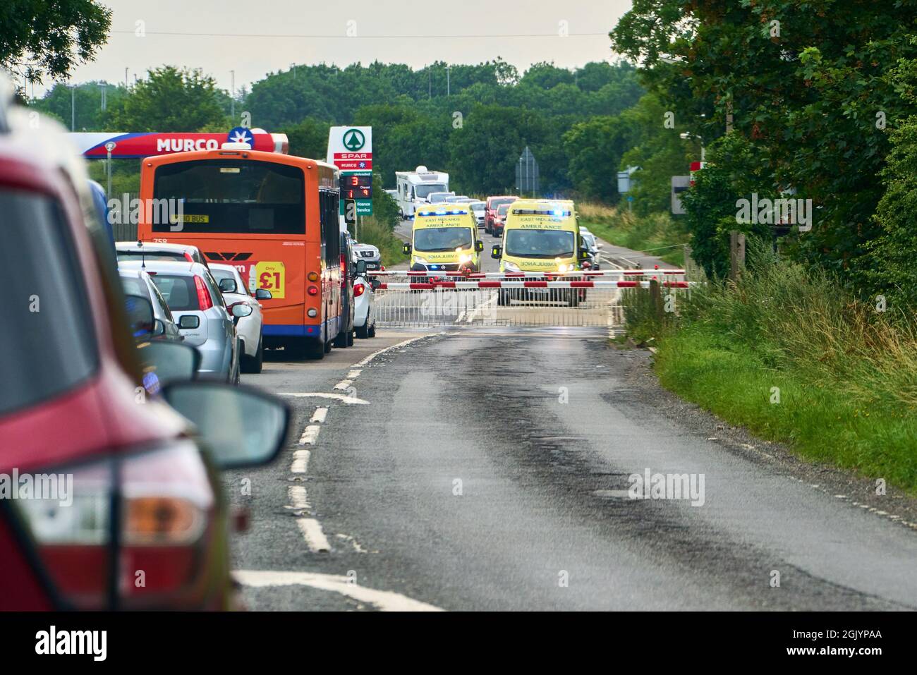 Dos ambulancias esperan en el cruce de nivel para que se levanten barreras en el A153 en Graylees Lincolnshire, lo que podría retrasar una respuesta de emergencia Foto de stock