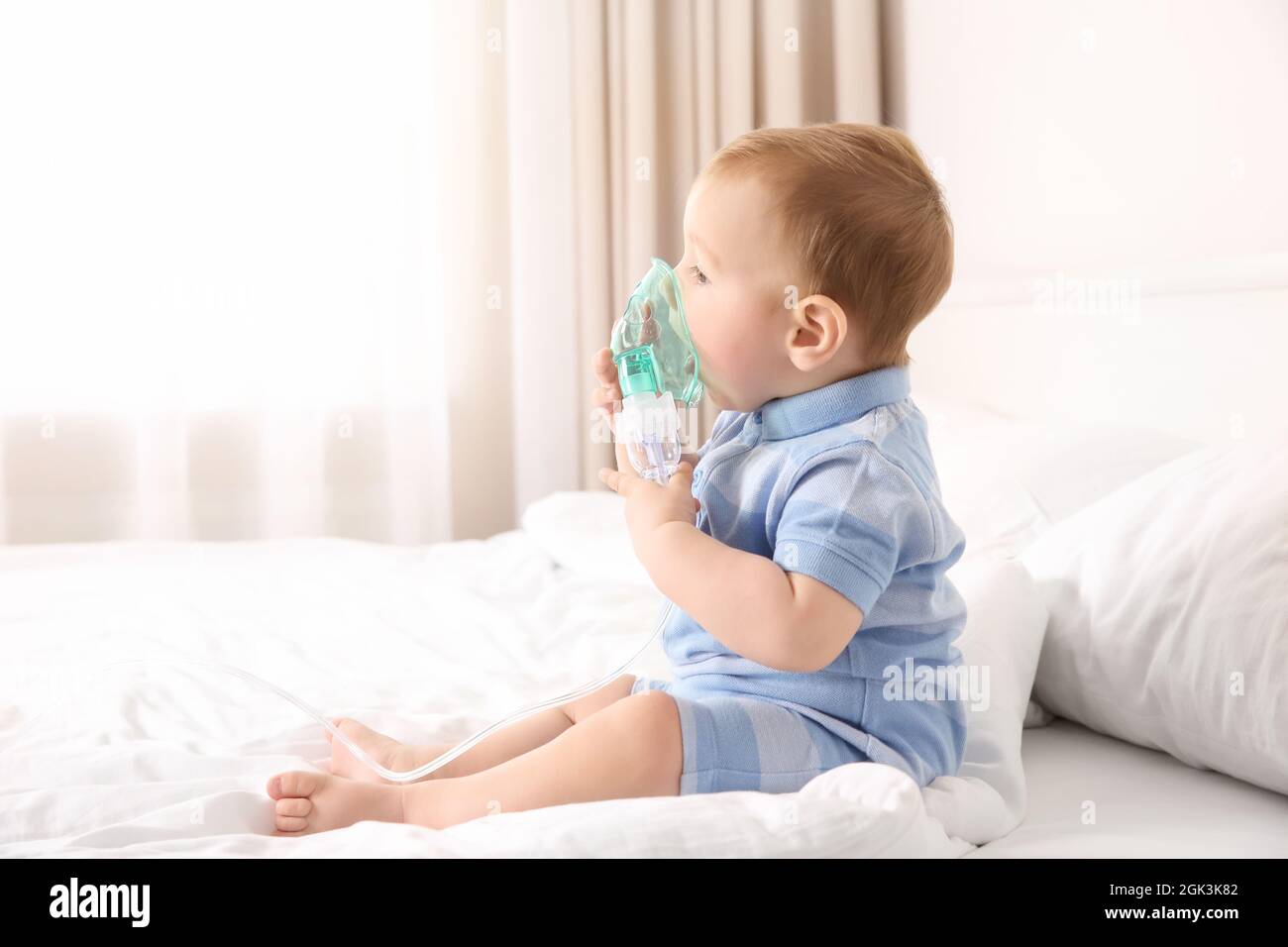 Bebé lindo con nebulizador sentado en la cama en casa. Concepto de atención  de salud Fotografía de stock - Alamy
