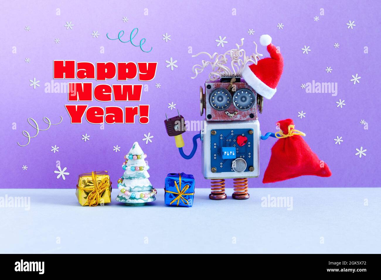 Divertido robot Santa está sosteniendo una bolsa con regalos. Árbol de  juguete de Navidad y cajas sobre fondo púrpura-azul con copos de nieve  cayendo. Navidad de Año Nuevo Fotografía de stock -