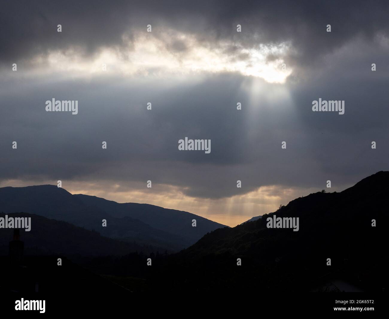 Un pozo de luz solar que se rompe a través de las nubes sobre Ambleside, Lake District, Reino Unido. Foto de stock