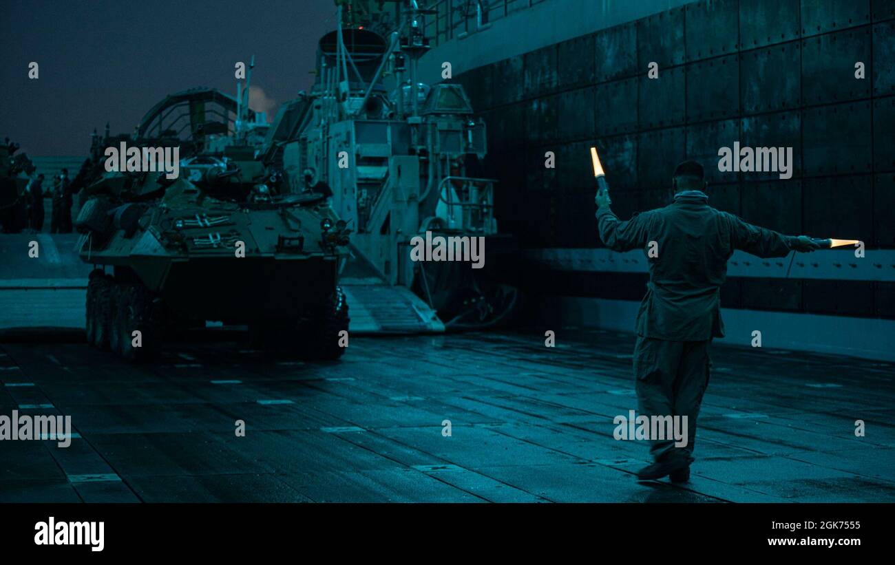 OCÉANO PACÍFICO (Agosto 21, 2021) Un Sailor de EE.UU. Con Unidad de Artesanía de Asalto 5, guía un vehículo blindado ligero en la cubierta de pozo del muelle de transporte anfibio USS Portland (LPD 27), 21 de agosto. Portland, parte del USS Essex Amphibious Ready Group, junto con la Unidad Expedicionaria Marina 11th, está operando en el área de responsabilidad de la Flota 7th de los EE.UU. Para mejorar la interoperabilidad con aliados y socios y servir como fuerza de respuesta para defender la paz y la estabilidad en la región del Indo-Pacífico. Foto de stock