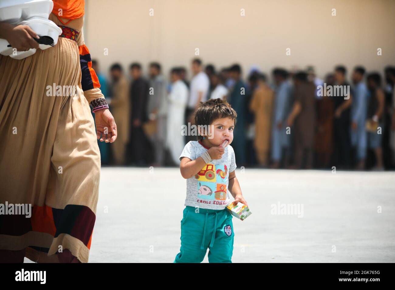 Un niño afgano lleva su jugo del comedor con su madre en el CENTCOM AOR, 21 de agosto de 2021. Los miembros del servicio de los Estados Unidos están ayudando al Departamento de Estado con una Operación de Evacuación de No-Combatientes (NEO) en Afganistán. Foto de stock