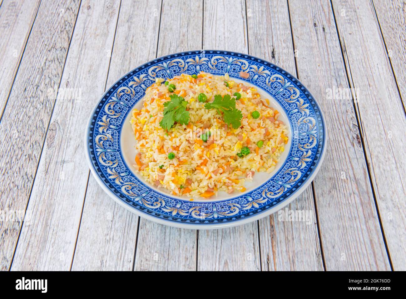 Tres delicias chinas arroz dentro de un hermoso plato con borde azul sobre mesa blanca Foto de stock