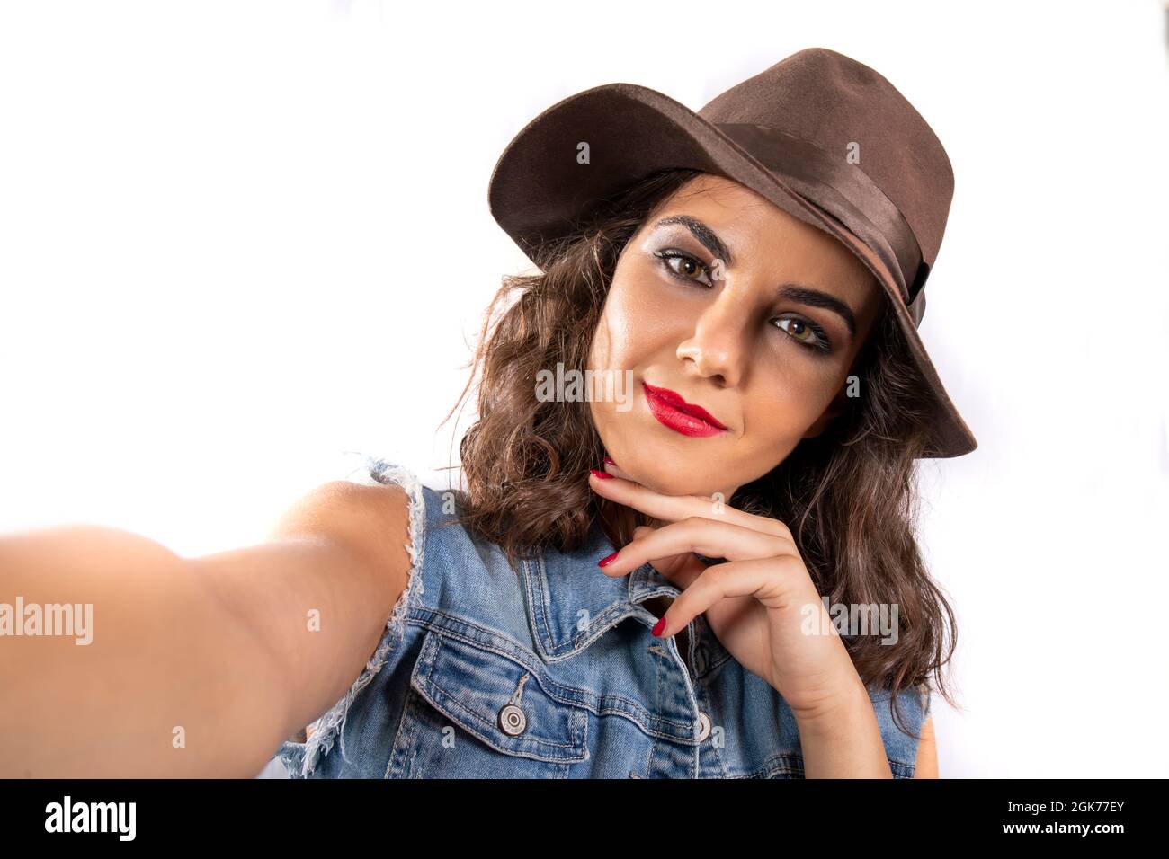 Manía selfie! Mujer joven atractiva con un sombrero marrón y un conjunto de  jeans tomando una selfie. Mirada intensa y soñadora subrayada por el  maquillaje y los ojos Fotografía de stock -