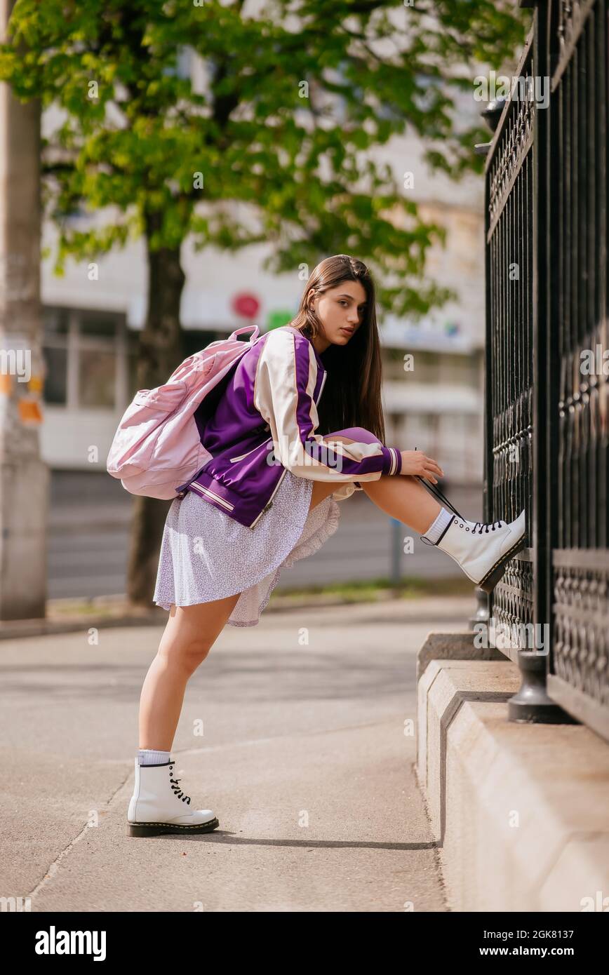 Mujer joven atando sus cordones en sus botas blancas durante el paseo por  la ciudad Fotografía de stock - Alamy