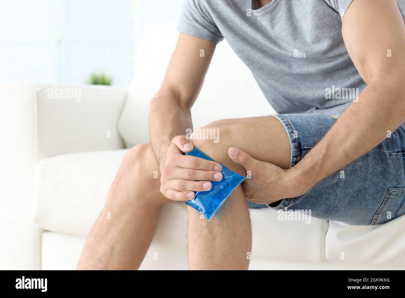 Hombre joven aplicando compresas frías en la pierna en casa Fotografía de  stock - Alamy