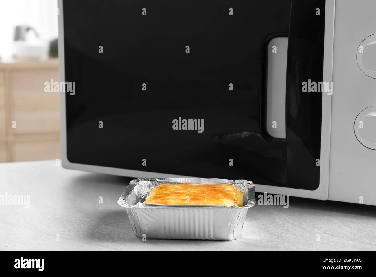 Cazuela de lámina de estaño para hornear cerca de microondas sobre la mesa  Fotografía de stock - Alamy