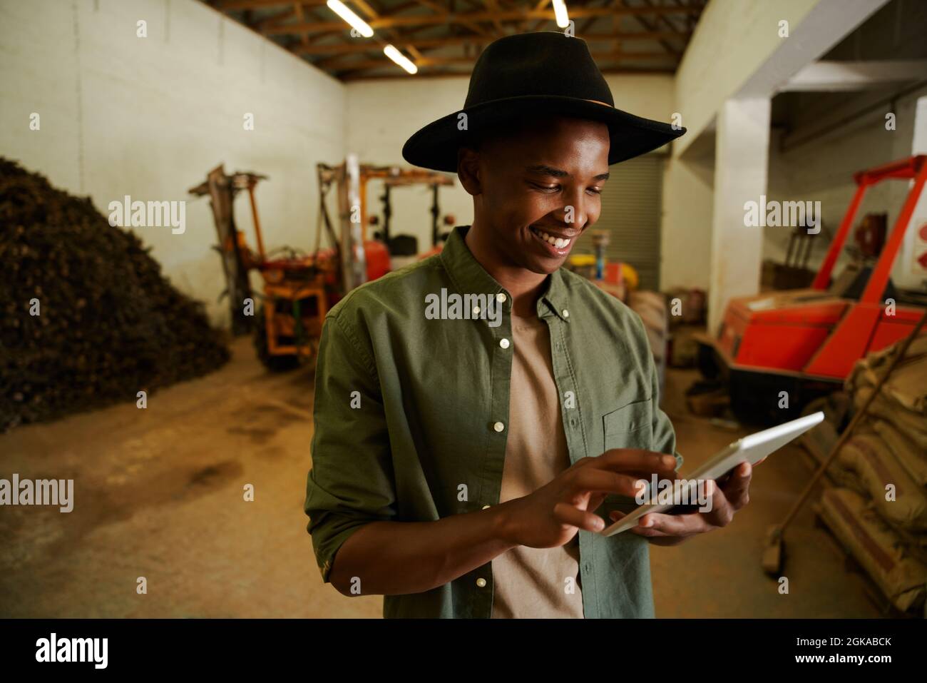 Granjero africano americano mecanografiando en la tableta digital de pie en el cobertizo Foto de stock