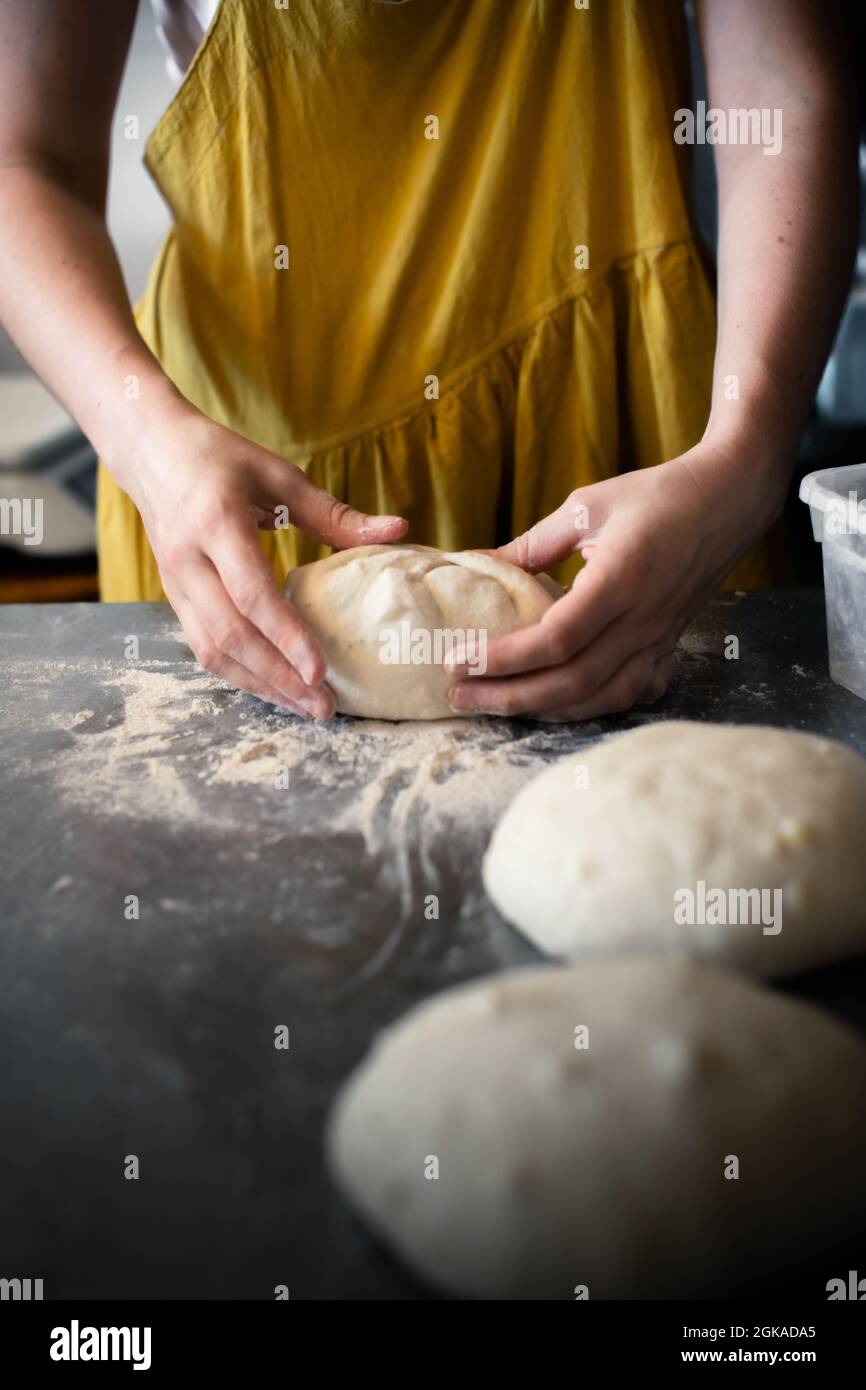 Mujer panadero forma pan en una mesa de acero en una panadería Foto de stock
