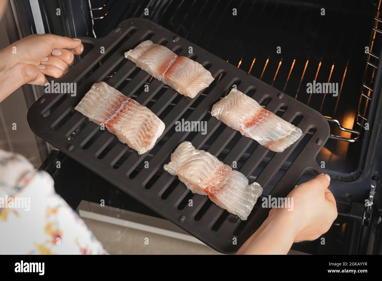 Mujer poniendo broiler pan con rodajas de filete de pescado al horno  Fotografía de stock - Alamy