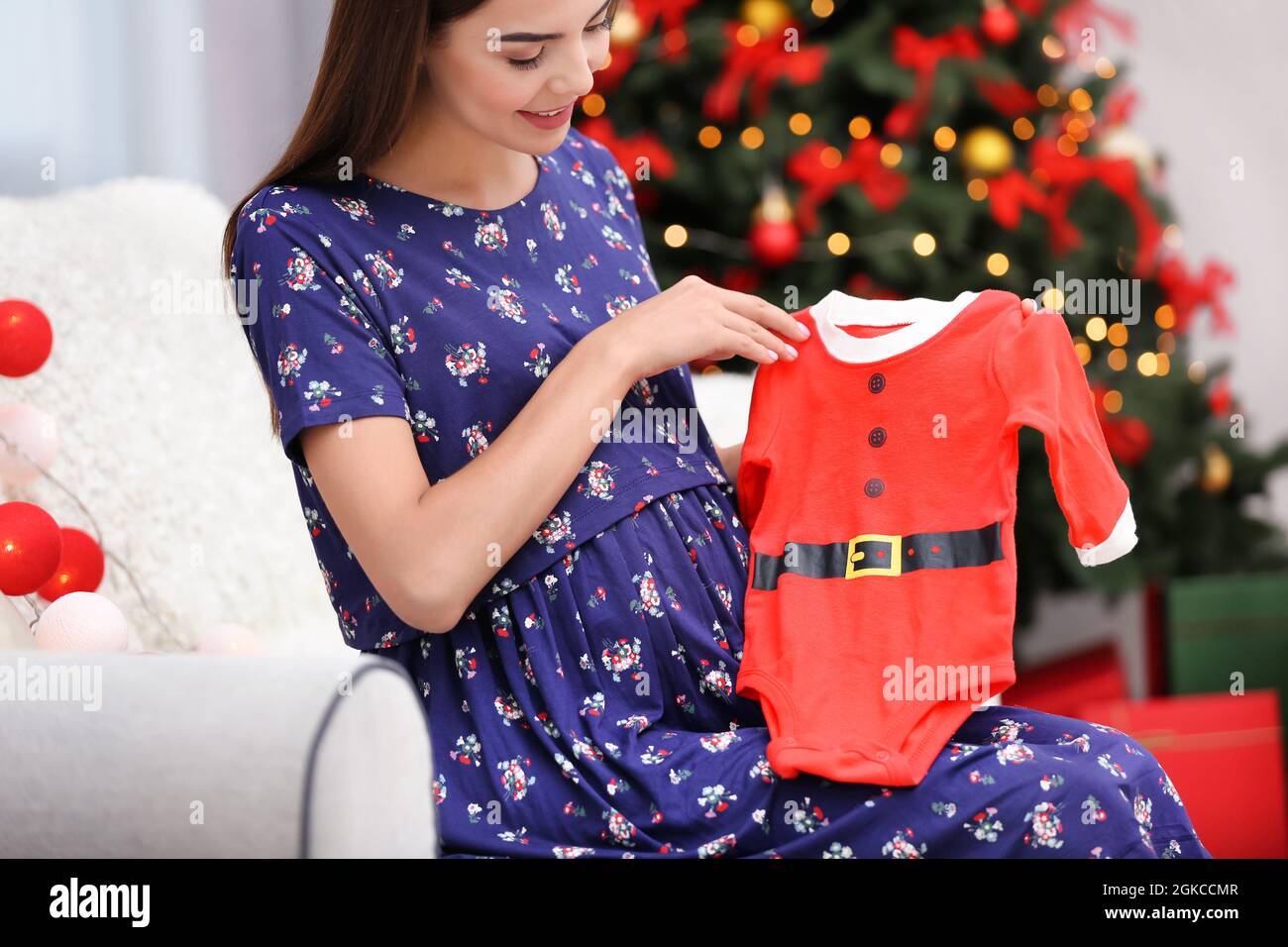 Mujer embarazada feliz con traje de bebé de Santa Claus la habitación decorada para Navidad de stock - Alamy