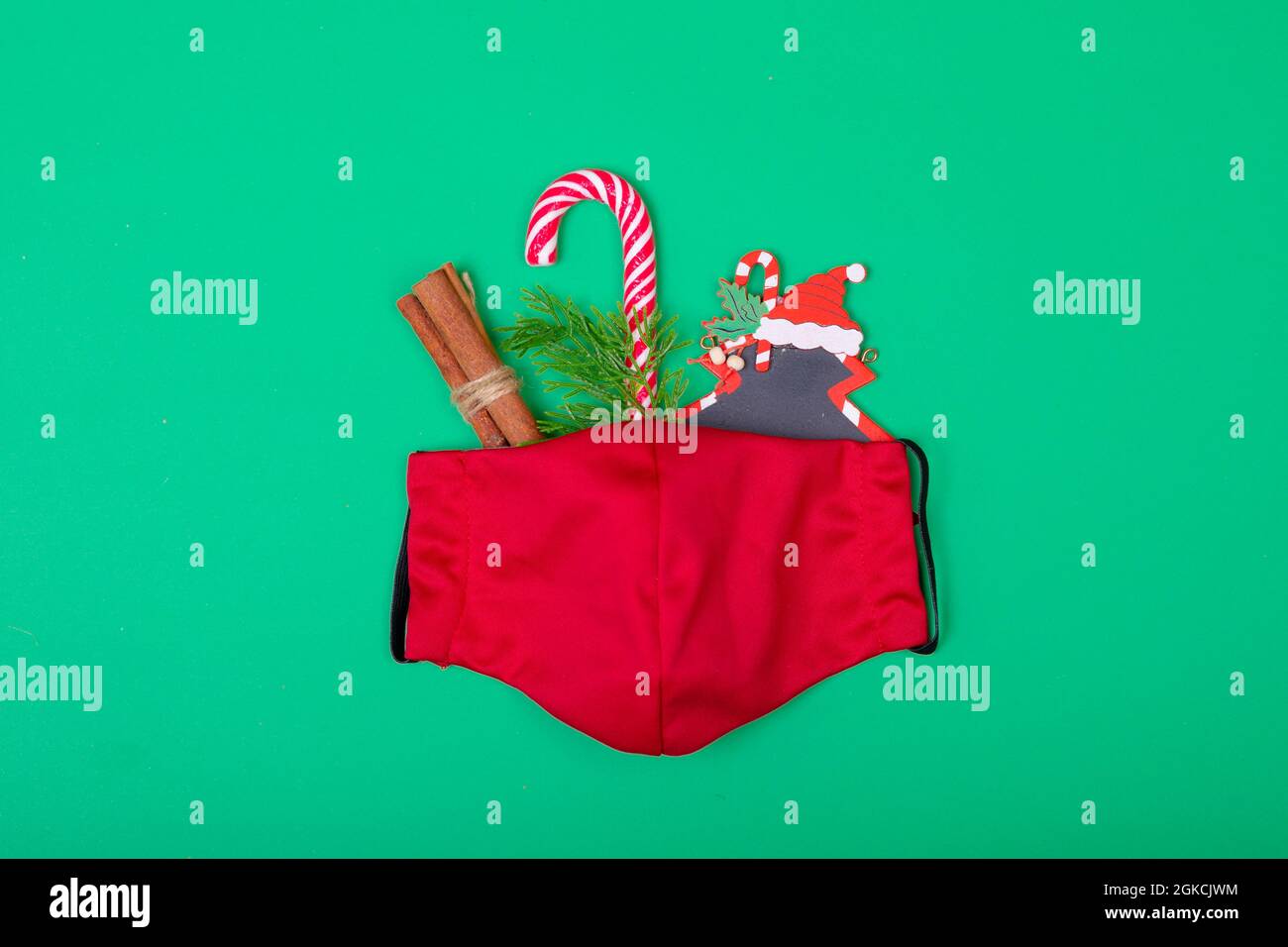 Composición de la máscara roja de la cara con decoraciones de Navidad sobre fondo verde Foto de stock
