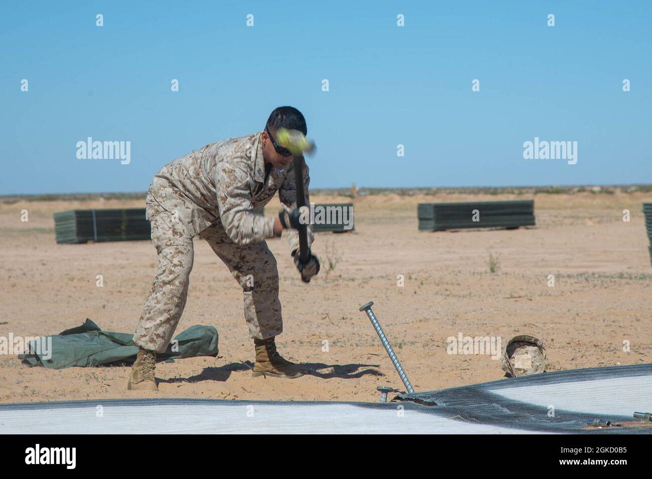 Justin Failma, un oficial de operaciones, con el destacamento de apoyo del ala marina 24, Marine Aircraft Group 24, 1st Marine Aircraft Wing, asignado a Marine Aviation Weapons and Tactics Squadron One (MAWTS-1), estacas de martillos para una aplicación práctica del aeródromo expedicionario, durante el curso de Instructor de Armas y Tácticas (WTI) 2-21, En el Aeródromo Auxiliar II, cerca de Yuma, Ariz, 16 de marzo de 2021. El curso WTI es un evento de capacitación de siete semanas organizado por MAWTS-1, que proporciona formación táctica avanzada estandarizada y certificación de las calificaciones de instructores de la unidad para apoyar la aviación marina TR Foto de stock