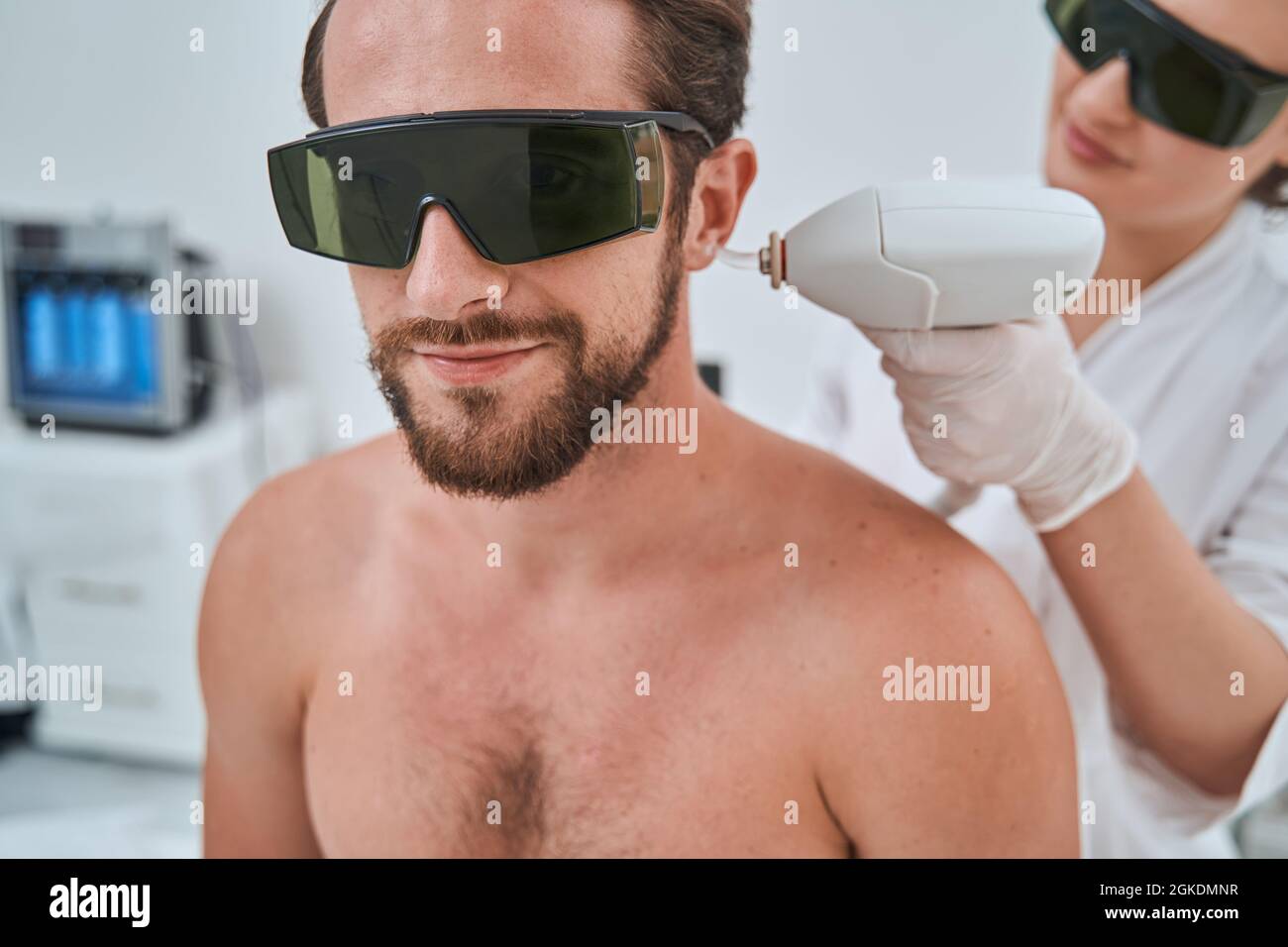 El hombre lleva gafas protectoras durante el tratamiento láser de  eliminación del vello de las orejas Fotografía de stock - Alamy