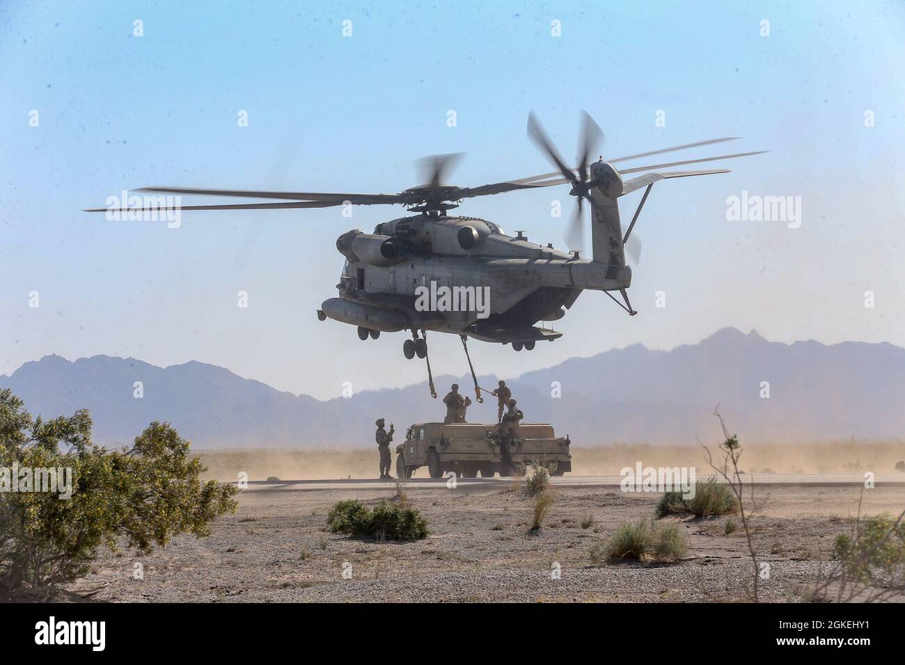 Marines de EE.UU. Asignados al Batallón de Logística de Combate 13, Regimiento de Logística de Combate 17, Grupo de Logística Marina de 1st, conducen un elevador pesado externo que involucra un Super Stallion CH-53E, y dos Humvees, en apoyo del curso de Instructor de Armas y Tácticas (WTI) 2-21, en el aeródromo Auxiliar II, cerca de Yuma, Arizona, 31 de marzo de 2021. El curso WTI es un evento de capacitación de siete semanas organizado por el Escuadrón de Armas y Tácticas de Aviación Marina, que proporciona entrenamiento táctico avanzado estandarizado y certificación de las calificaciones del instructor de la unidad para apoyar el entrenamiento y preparación de la aviación marina, y ayuda en DEVEL Foto de stock