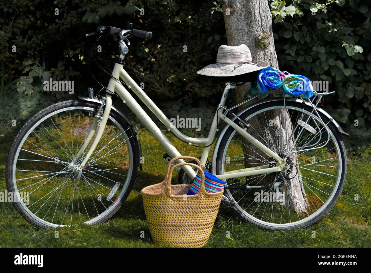 Bicicletas de estilo tradicional crema para mujeres con toallas y sombrero de sol preparado para la playa, West Wittering, Nr.Chichester, West Sussex, Inglaterra Foto de stock