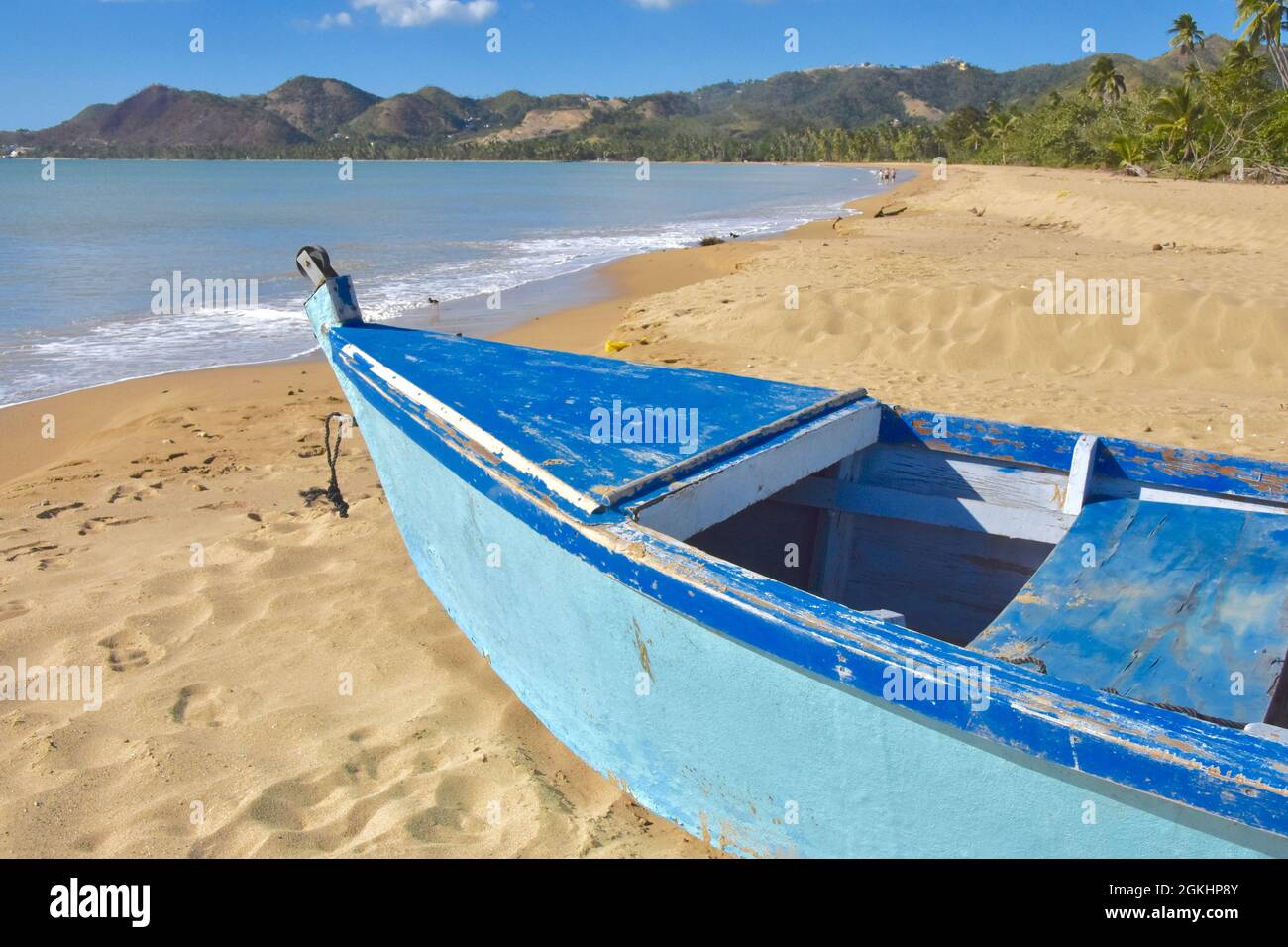Tradicional barco de pesca caribeño en una playa de arena con colinas en la distancia. Anasco, Puerto Rico, Estados Unidos. Espacio de copia. Foto de stock