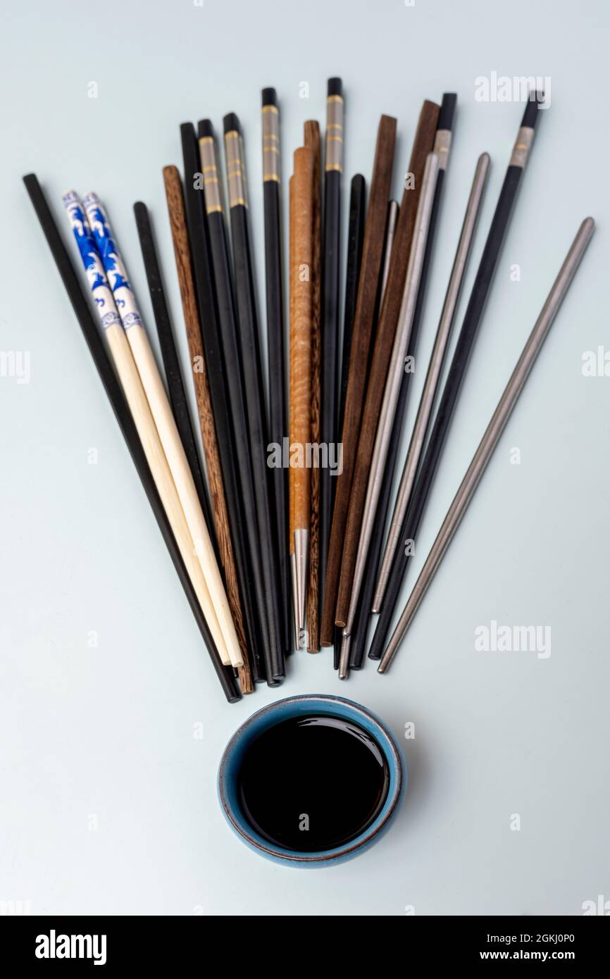 Palillos chinos de diferentes texturas, colores y materiales, un tazón azul  con salsa de soja sobre un fondo azul cielo Fotografía de stock - Alamy