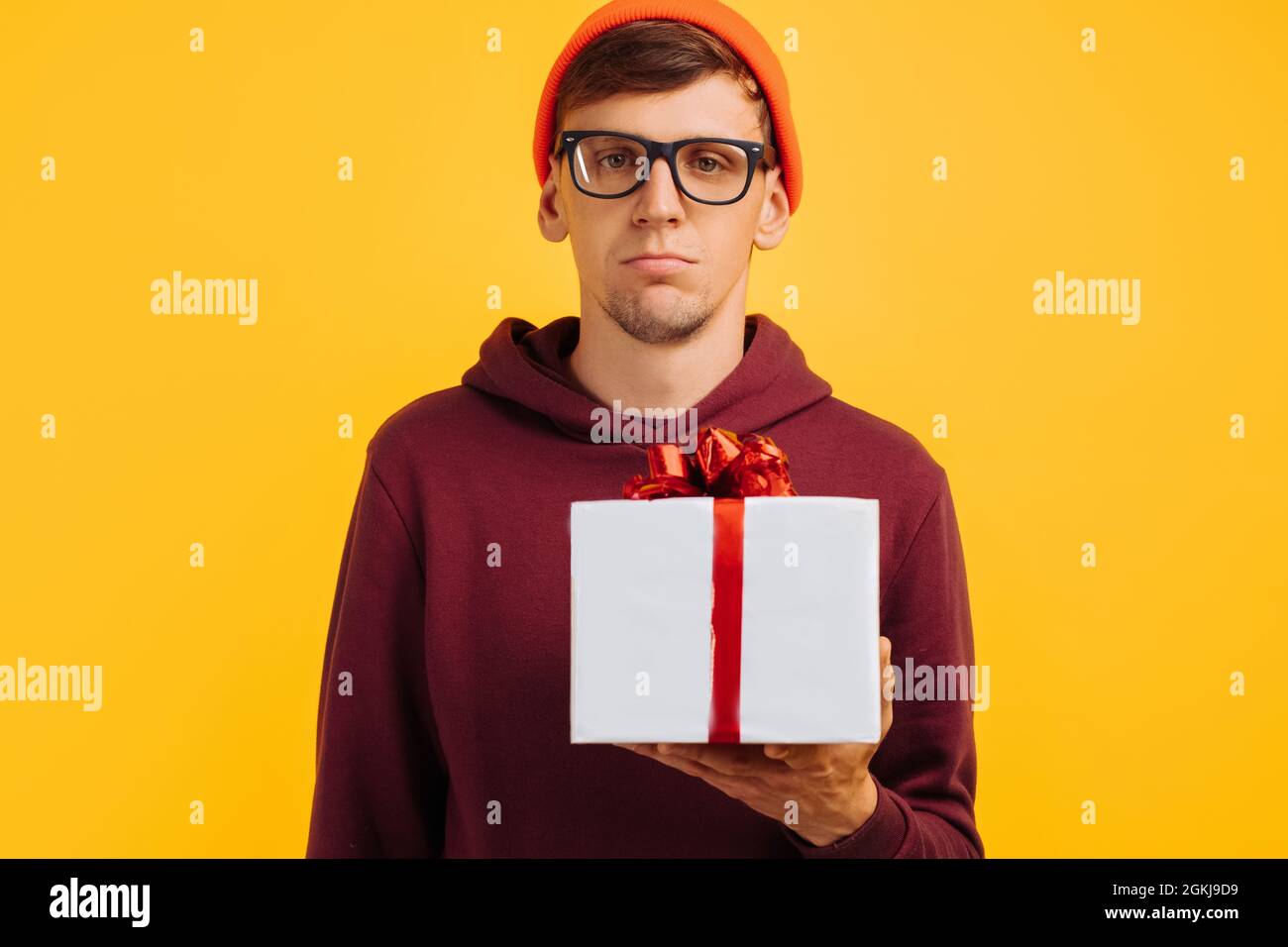 un chico joven infeliz con un sombrero naranja con gafas y un suéter rojo  no está contento con su regalo, humor festivo, regalos de año nuevo  Fotografía de stock - Alamy