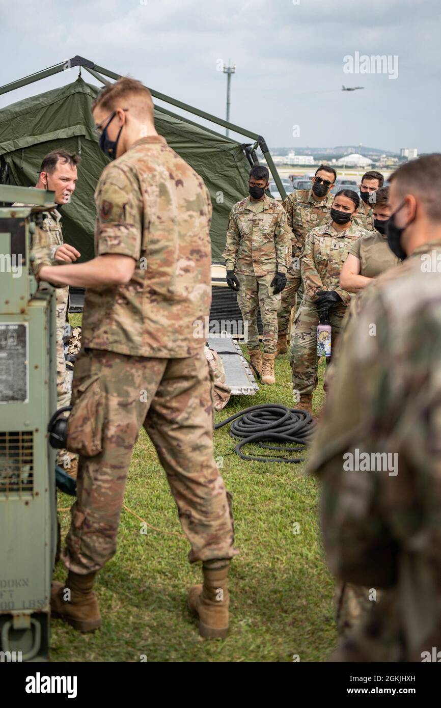 Los miembros de la Fuerza Aérea y Espacial observan una demostración sobre cómo operar un generador en la instalación de una estación de operación avanzada durante un ejercicio de empleo de combate ágil en la Base Aérea de Kadena, Japón, 4 de mayo de 2021. ACE hula la capacidad de respuesta y ajuste de diferentes bases y ramas para defender mejor el Indo-Pacífico. Foto de stock