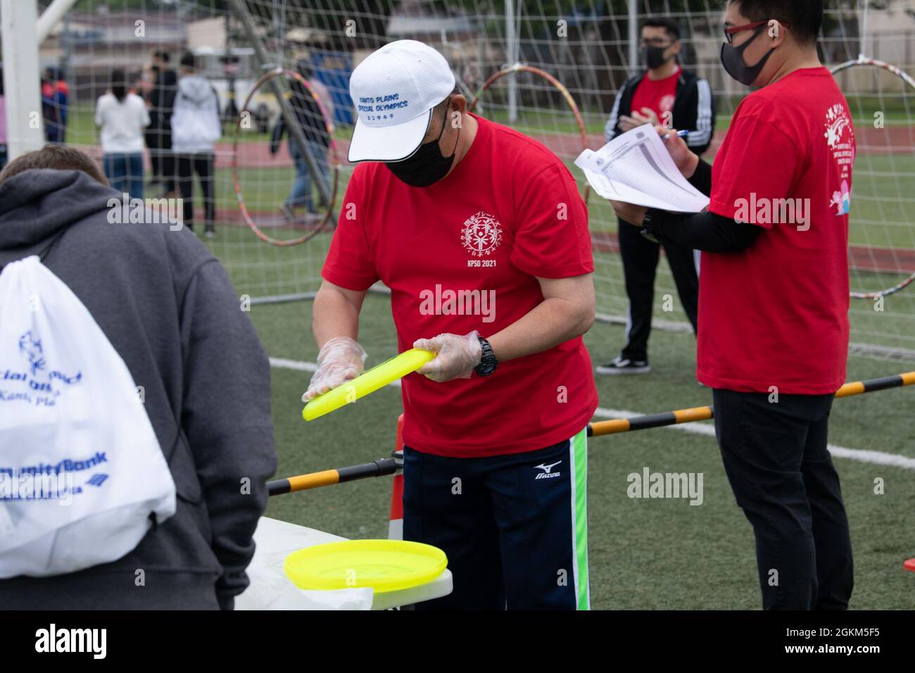 Un voluntario limpia un disco volador durante los Juegos Olímpicos Especiales de Kanto Plains en la Base Aérea de Yokota, Japón, 22 de mayo de 2021. Este año se celebra el KPSO anual de 42nd, un evento atlético en el que participan familias de todas las llanuras de Kanto y el área metropolitana de Tokio. Foto de stock