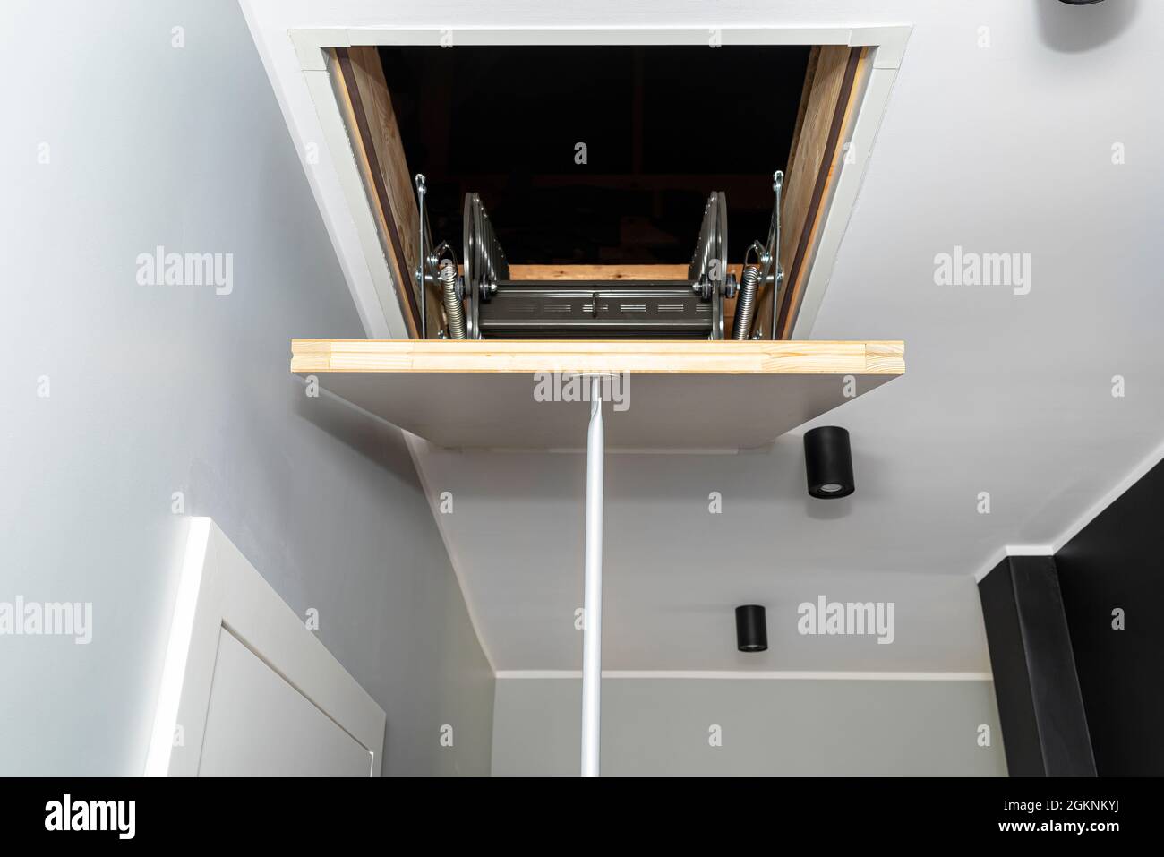 Escaleras de metal plegables al ático en el techo, trampilla cerrada con un  tubo para la apertura, aspecto moderno Fotografía de stock - Alamy