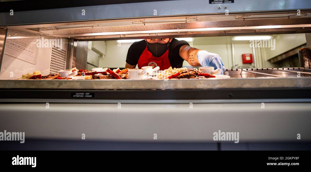 U.S. Marine Corps Cpl. Justin Rivera, especialista en servicio de alimentos en la Sede y Batallón de Apoyo, Marine Corps Installations Pacific, prepara comida durante el especialista en servicio de alimentos del concurso trimestral en Camp Kinser, Okinawa, Japón, 16 de junio de 2021. La competición de dos días comenzó con un examen escrito y oral donde los infantes de Marina son juzgados por su apariencia militar, conocimiento y portar. La segunda parte del evento se centró en las habilidades culinarias, sanitarias y nutritivas de los Marines mientras estaban bajo la atenta mirada de los evaluadores de garantía de calidad. Rivera es nativa de Housto Foto de stock