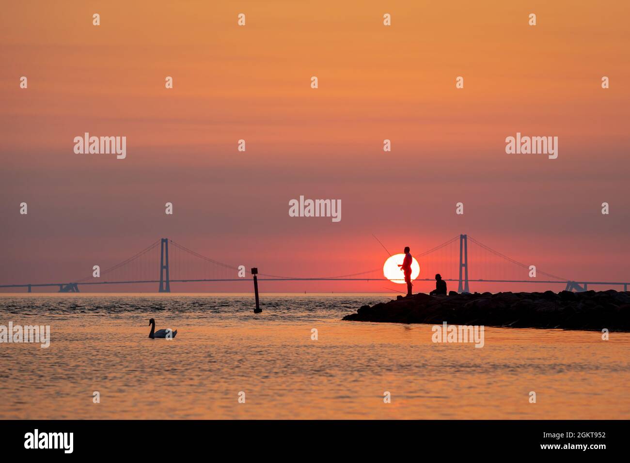 Silueta de dos hombres pescando con el puente Great Belt Bridge en el fondo, Dinamarca Foto de stock