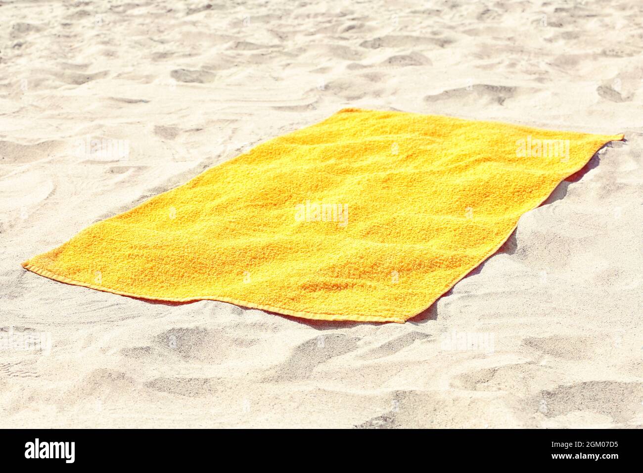 Toalla de playa amarilla sobre arena Fotografía de stock - Alamy