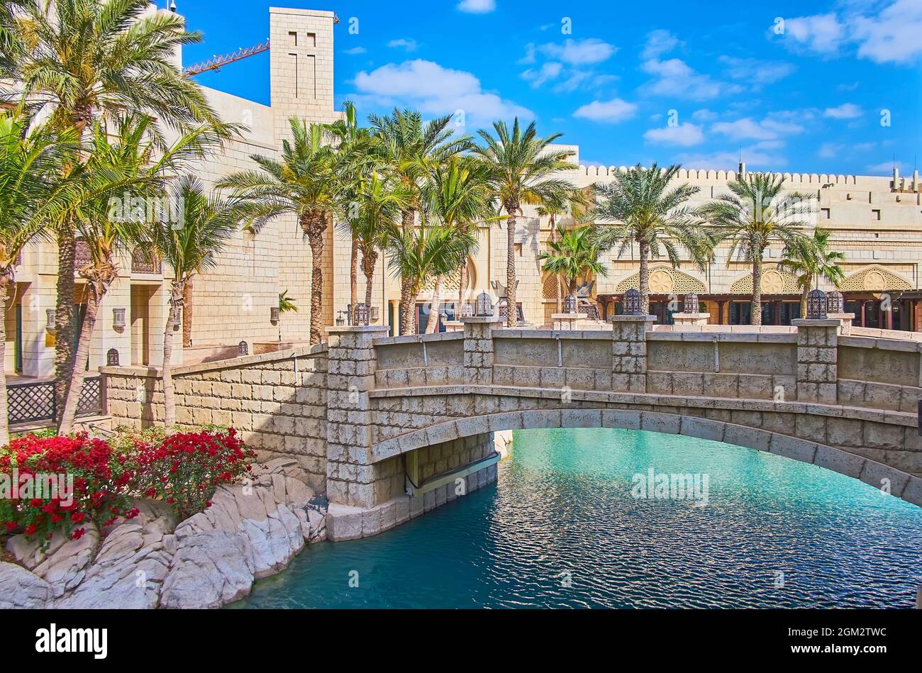 El pequeño puente peatonal de piedra sobre el canal, que conecta la isla de Fort con el continente del mercado de Souk Madinat Jumeirah, Dubai, Emiratos Árabes Unidos Foto de stock