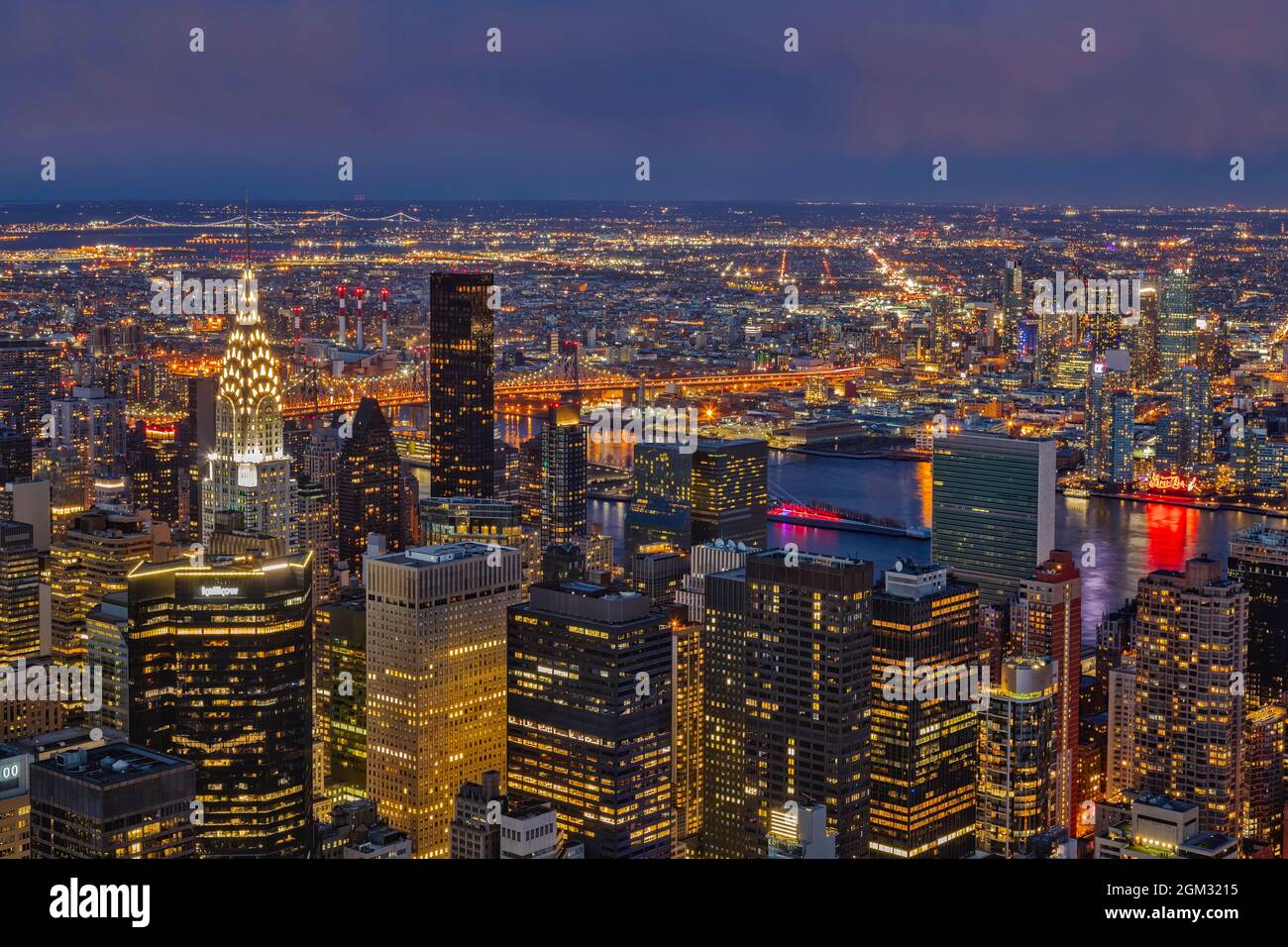 NYC Twilight - Vista superior del horizonte iluminado del centro de Manhattan East Side incluyendo el emblemático edificio de estilo Art Deco Chrysler junto con el Ed Koc Foto de stock