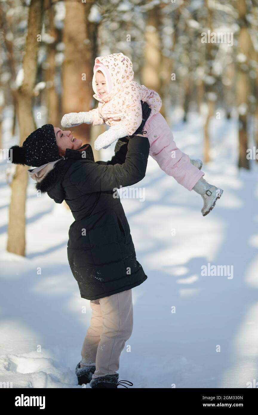 Mamá se divierte con el niño sobre fondo nevado de invierno Foto de stock