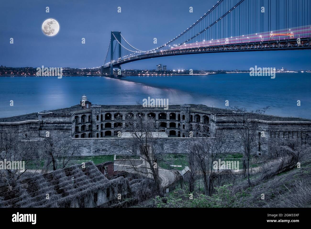 Verrazano Narrows Bridge Full Moon - Vista a Fort Wadsworth, el Verrazano Narrows Bridge, el puerto de Nueva York bajo una luna llena durante la hora azul Foto de stock