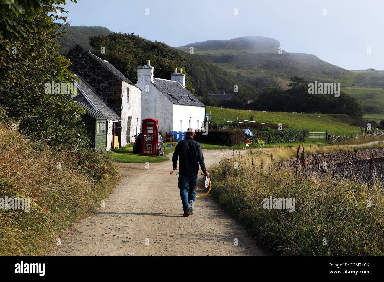 Hombre caminando a lo largo de la carretera principal en la Isla de Canna en las Hébridas Interiores de Escocia Foto de stock