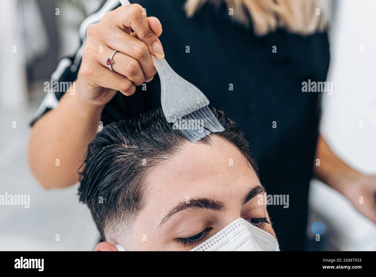 Un peluquero profesional aplica tinte para el cabello con un pincel a un  cliente en un salón de belleza