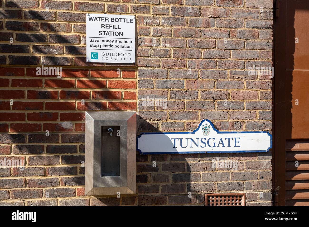 Estación de recarga de botellas de agua en el centro de la ciudad de Guildford, el letrero dice Ahorre dinero y ayude a detener la contaminación plástica Foto de stock