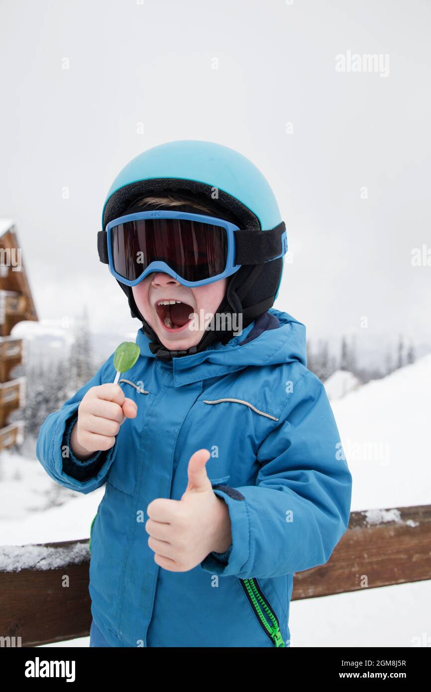 Pequeño niño en ropa de esquí, cascos y gafas, listo para ir a esquiar con  la caída de nieve Fotografía de stock - Alamy