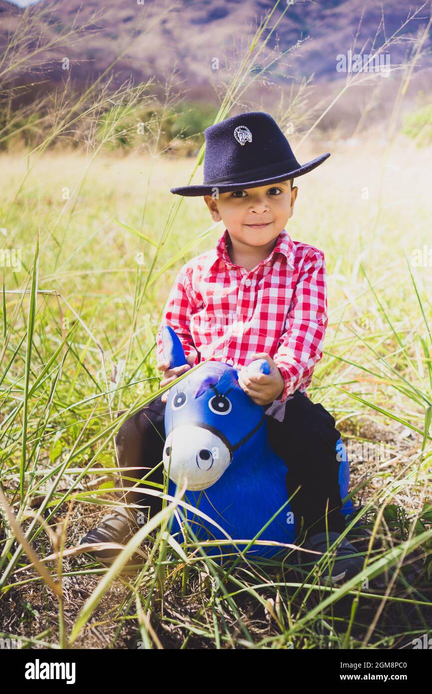 Niño blanco vestido como un vaquero, jugando en el bosque con su caballo de  juguete. Retrato infantil para el día de los niños, moda infantil, moda  rural Fotografía de stock - Alamy
