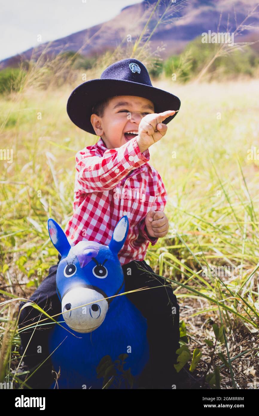 Niño vestido como un vaquero, jugando el bosque con su caballo de juguete. Retrato infantil para el día de los niños, moda infantil, moda rural Fotografía de stock - Alamy