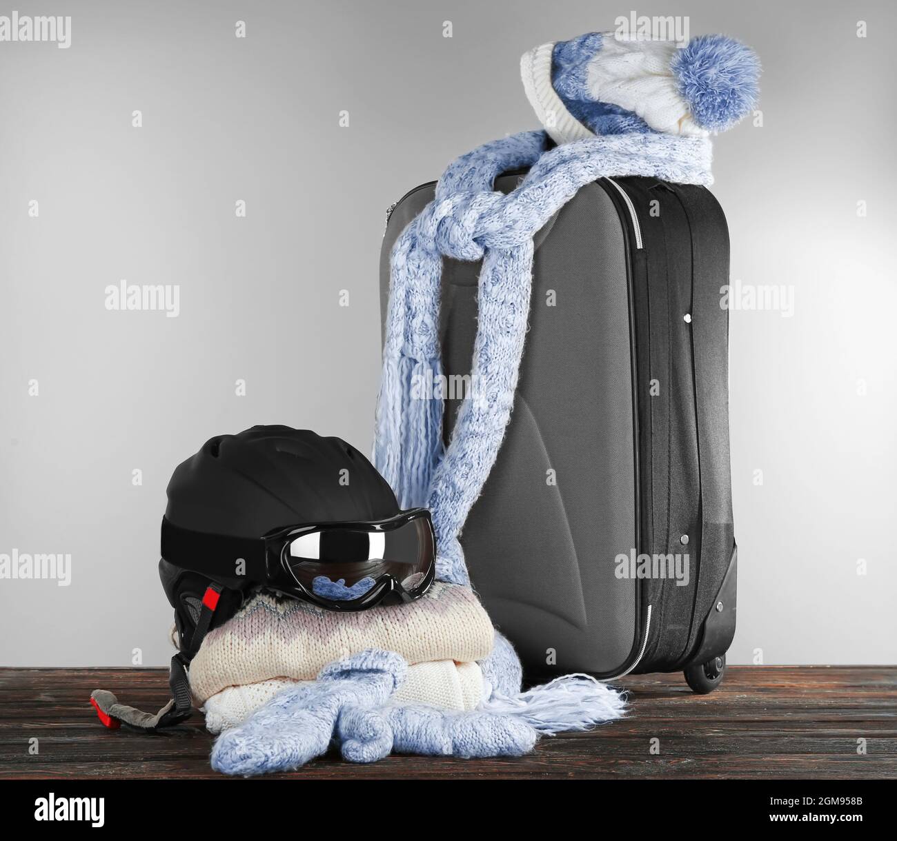 Maleta con ropa de abrigo y ropa de esquí en tabla de madera contra un  fondo gris. Concepto de vacaciones de invierno Fotografía de stock - Alamy